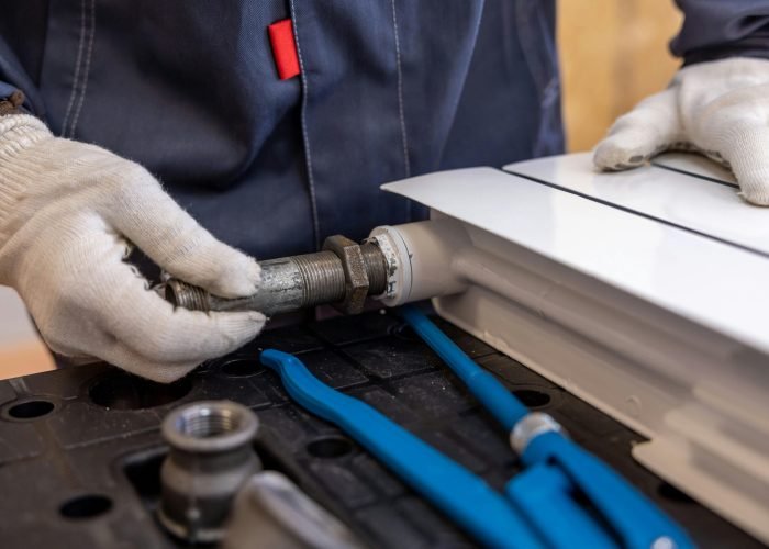 Close-up of a plumber installing a radiator pipe using specialized tools.